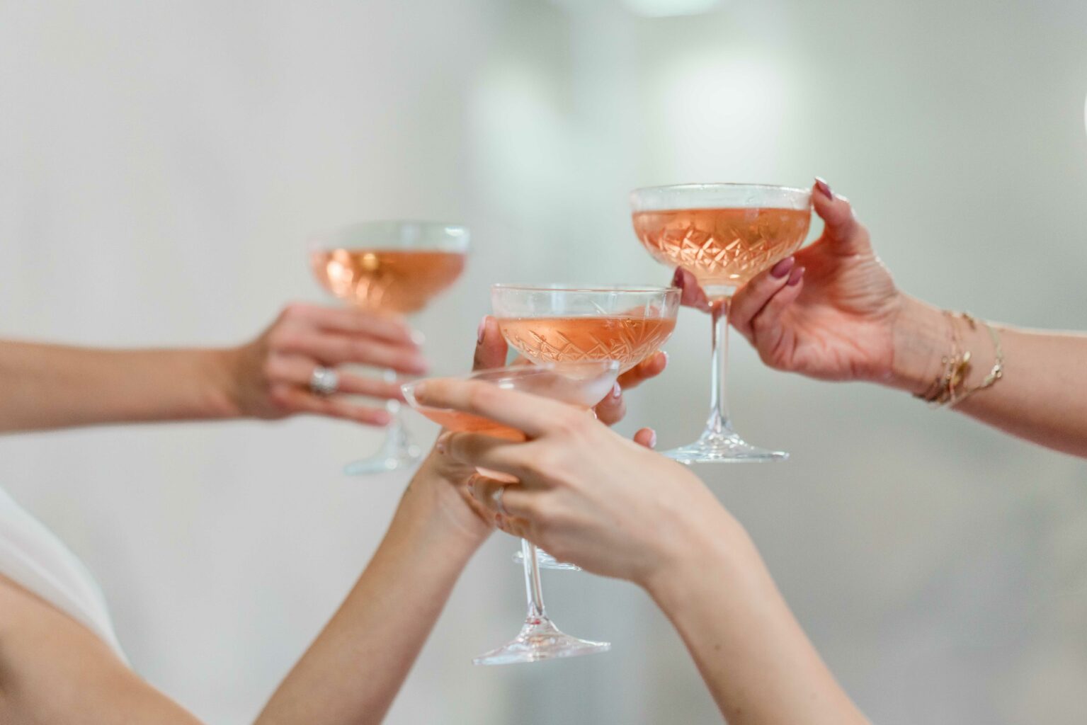 Vier Hände, die mit einem Champagner Glas anstoßen
